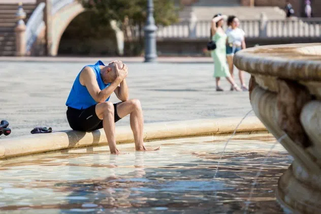 Người đàn ông giải tỏa nắng nóng tại một đài phun nước ở Seville. Ảnh: Getty