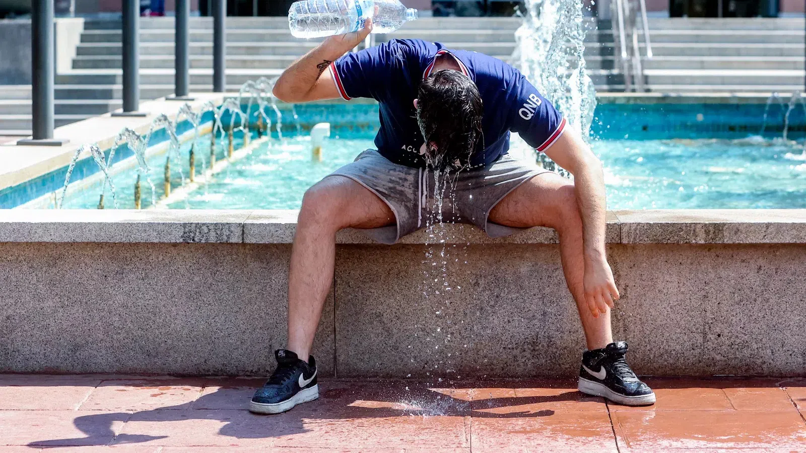 Một thanh niên dội nước để làm dịu nắng nóng tại Madrid. Ảnh: Getty