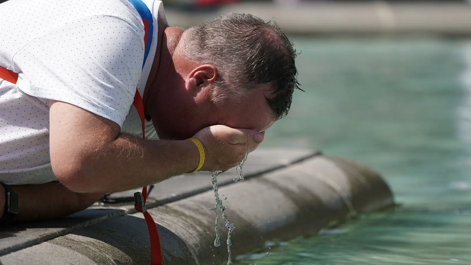 Một người đàn ông tạt nước vào mặt để giải nhiệt.