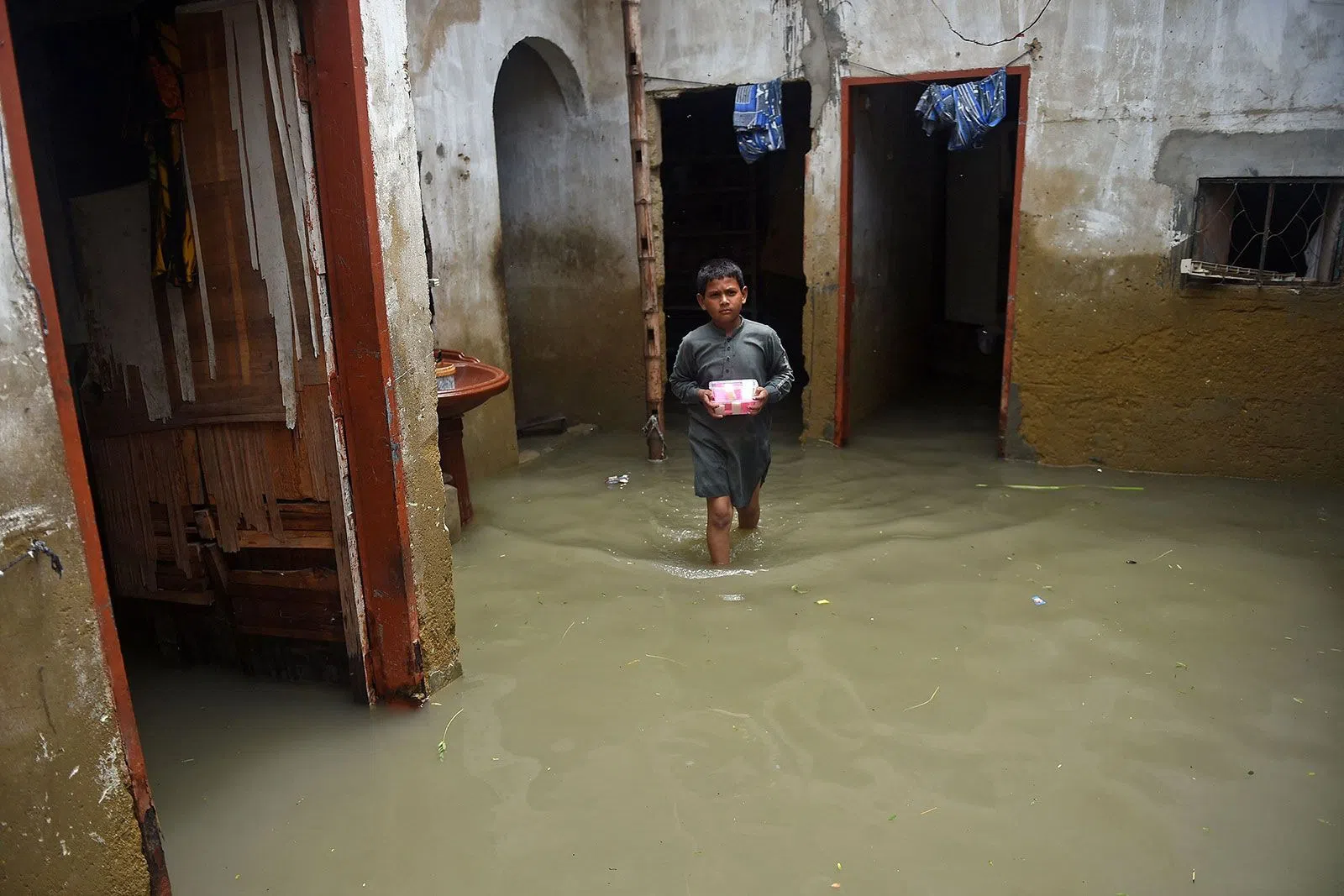 Một cậu bé lội qua ngôi nhà ngập lụt của mình ở Karachi. Ảnh: Getty