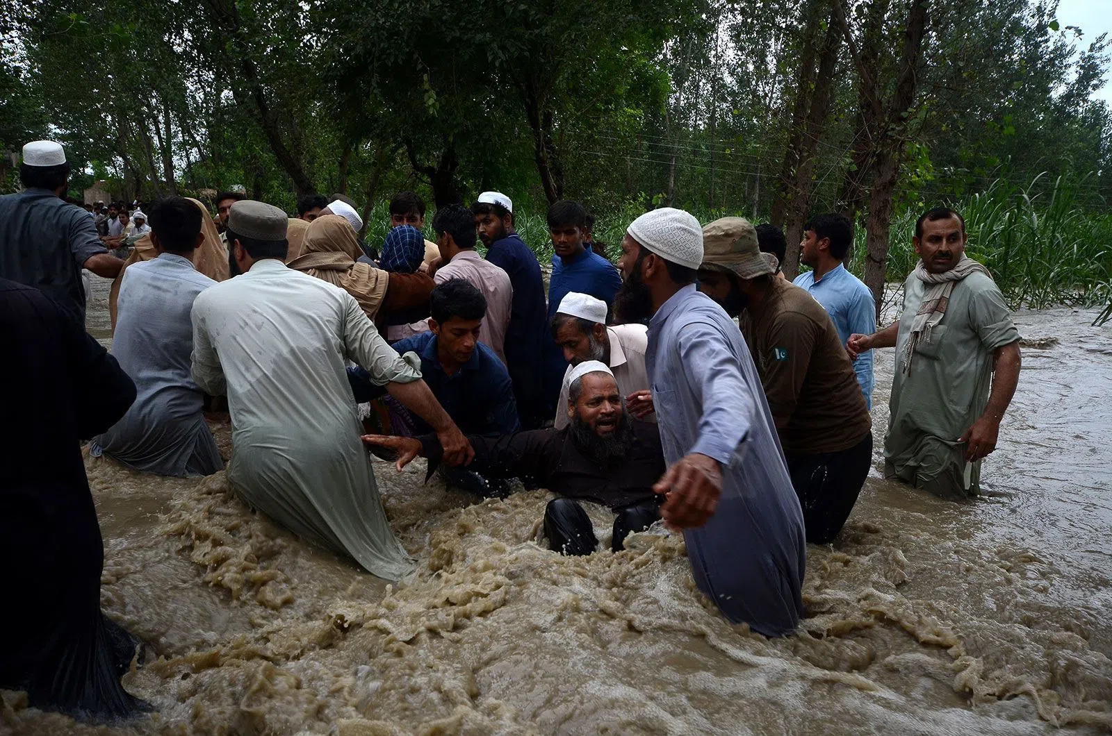 Người dân lội qua dòng nước lũ ở Dagai Mukram Khan, Pakistan, ngày 26/8. Ảnh: Getty