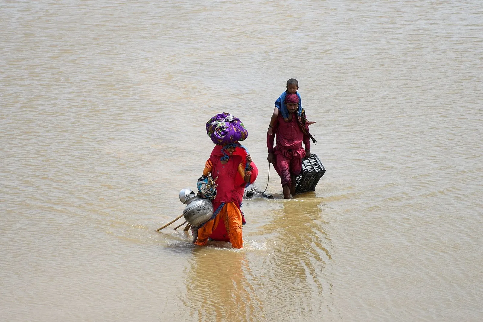 Một gia đình mang đồ đạc đi qua dòng nước lũ ở Jamshoro, Pakistan, ngày 26/8. Ảnh: Reuters