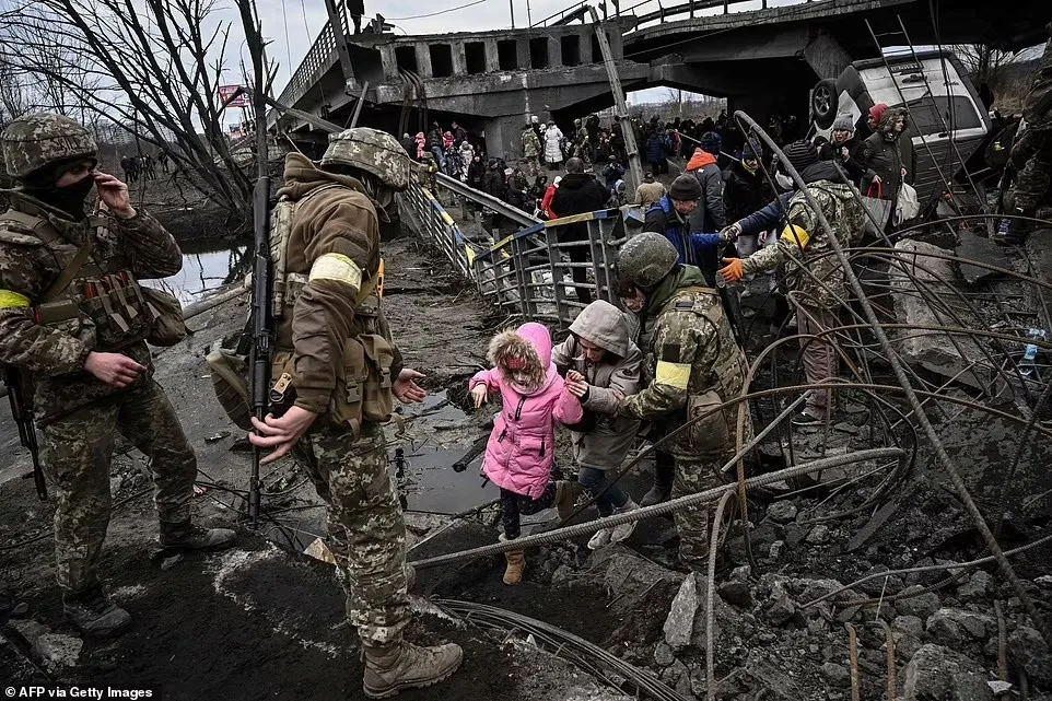 Mọi người băng qua một cây cầu bị phá hủy khi họ di tản khỏi thành phố Irpin, phía tây bắc Kyiv.
