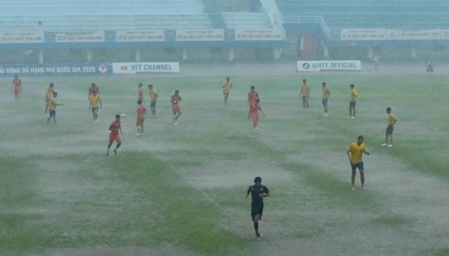 Cầu thủ hai bên thi đấu dưới trời mưa lớn.