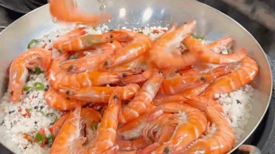 Rang muối thật khô ráo rồi cho tôm vào đảo đều.