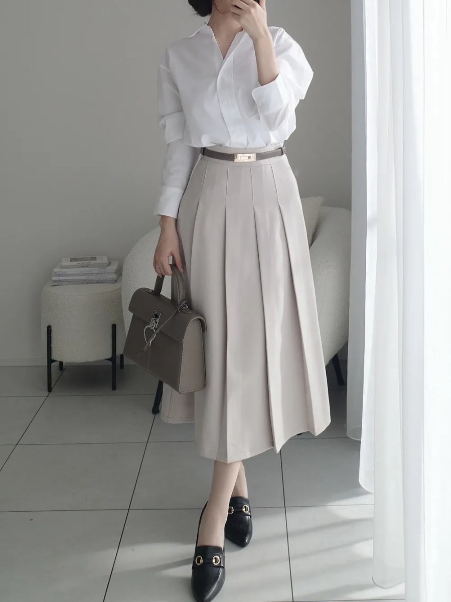 Outfit công sở thanh lịch với áo sơ mi trắng và chân váy xếp ly chữ A. 