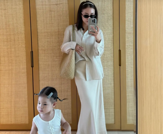 Cô kết hợp áo sơ mi kẻ sọc với chân váy suông để tạo nên bộ trang phục chuẩn mốt.