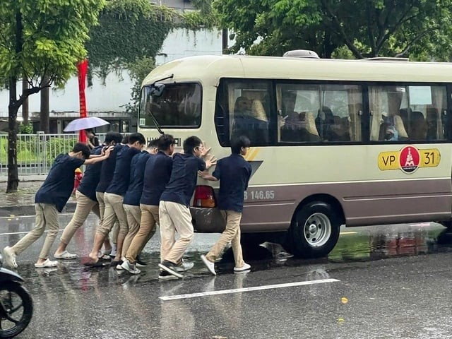 Nước ngập sâu khiến ô tô bị chết máy. Một nhóm học sinh phải xuống xe hỗ trợ tài xế đẩy xe trong sáng 25/8. (Ảnh: Lâm Black/OFFB)