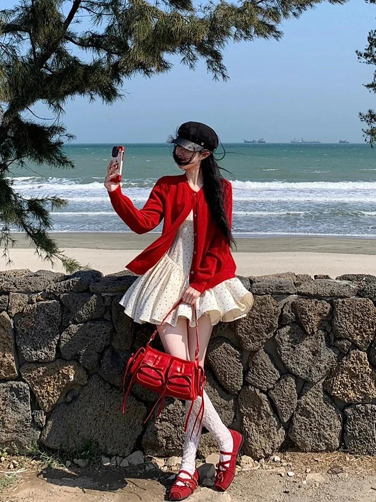 Cardigan đỏ phối cùng váy hai dây chấm bi ngắn tạo nên diện mạo ngọt ngào, nữ tính nhưng không kém phần nổi bật.