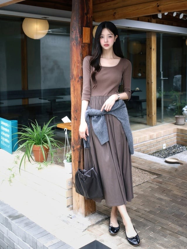 Một chiếc váy nâu tối giản kết hợp với áo len xám buộc ngang hông là công thức vừa ấm áp vừa thời thượng.