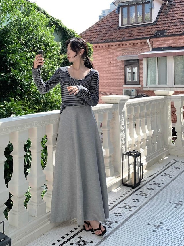 Một chiếc áo thun dài tay kết hợp với chân váy xám dài là công thức đơn giản mà hiệu quả