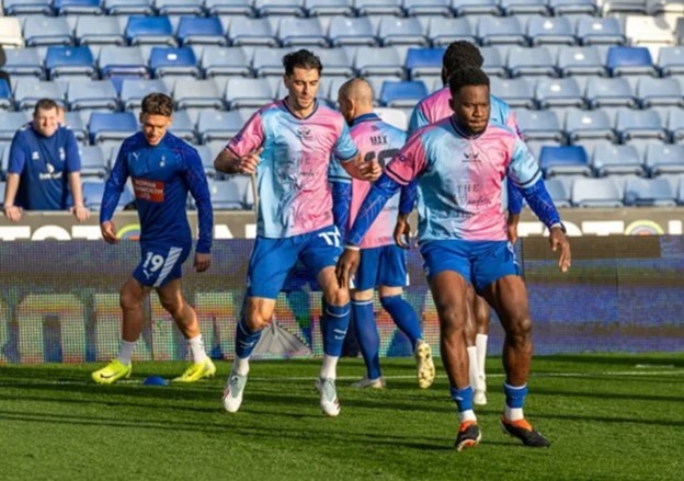 Các cầu thủ Oldham tập luyện trong trang phục màu hồng và xanh của Angels United.