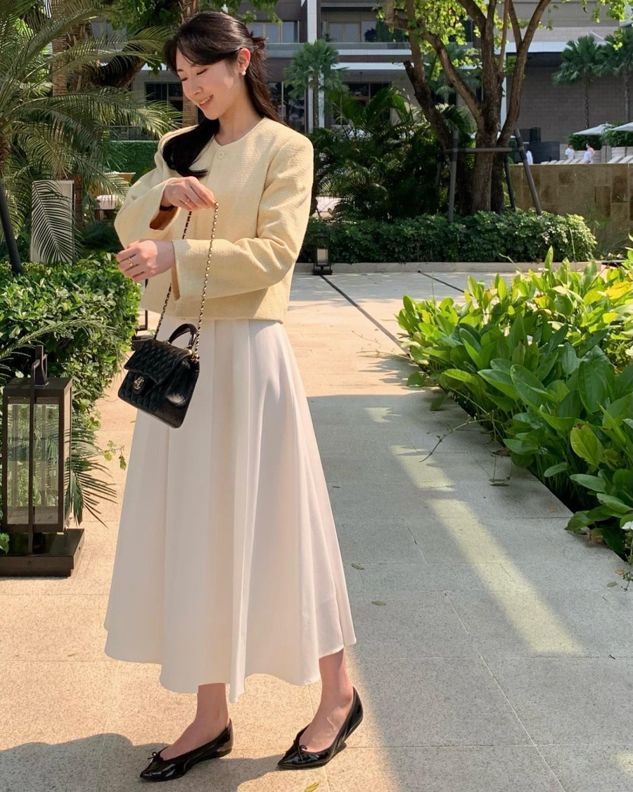 Chiếc áo dạ màu vàng kem giúp set váy trắng trở nên sang trọng, trẻ trung 