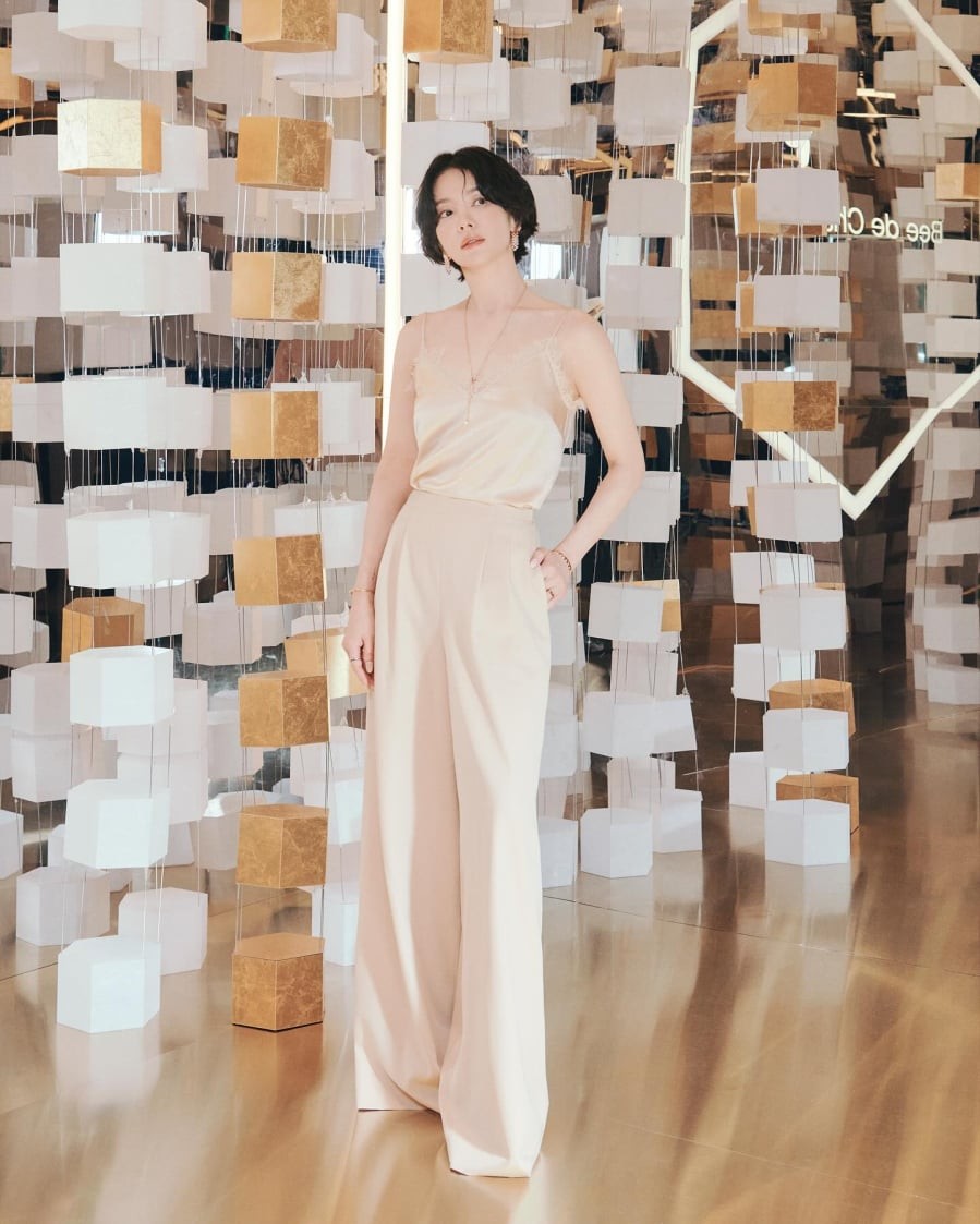 Kiểu sơ vin gọn gàng và trang sức vàng tạo nên điểm sáng sang trọng cho cả bộ đồ.