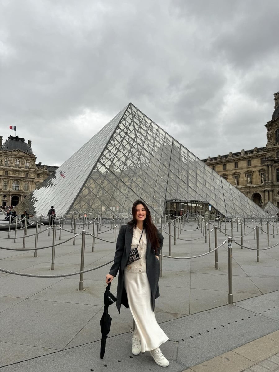 Sự kết hợp giữa cardigan mềm mại, chân váy trắng và áo dạ xám đậm mang đến tổng thể hài hòa giữa nét nữ tính và hiện đại. 