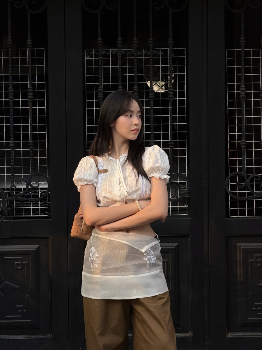 Chi tiết váy tạp dề layering phía ngoài trở thành điểm nhấn thú vị, giúp bộ trang phục thêm phần bắt mắt mà vẫn gọn gàng, không rối.

