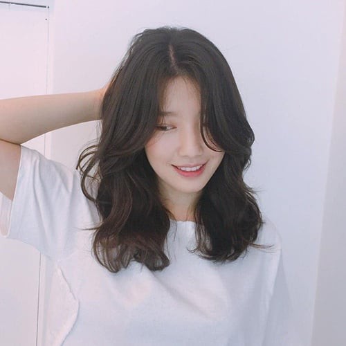 Khi đuôi tóc cong nhẹ vào phía trong, ánh nhìn sẽ được dẫn theo chiều dọc của mái tóc, tạo cảm giác gương mặt dài hơn. 