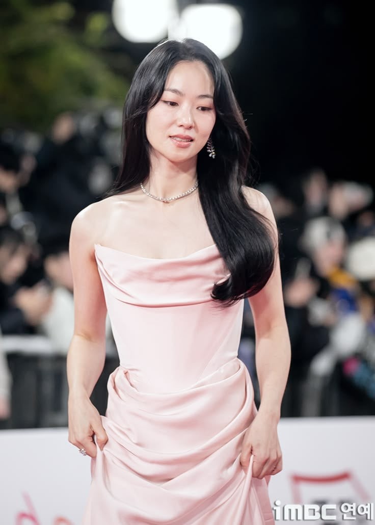 Một chiếc váy satin màu hồng pastel với phần cổ đổ mềm mại và các nếp xếp nhẹ giúp tôn lên vóc dáng thanh thoát của nữ diễn viên.