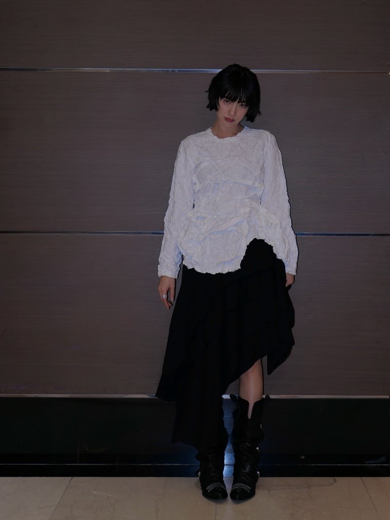 Một trong những bản phối được đánh giá cao là sự kết hợp giữa áo blouse trắng có hiệu ứng xếp nếp cùng chân váy bất đối xứng màu đen.