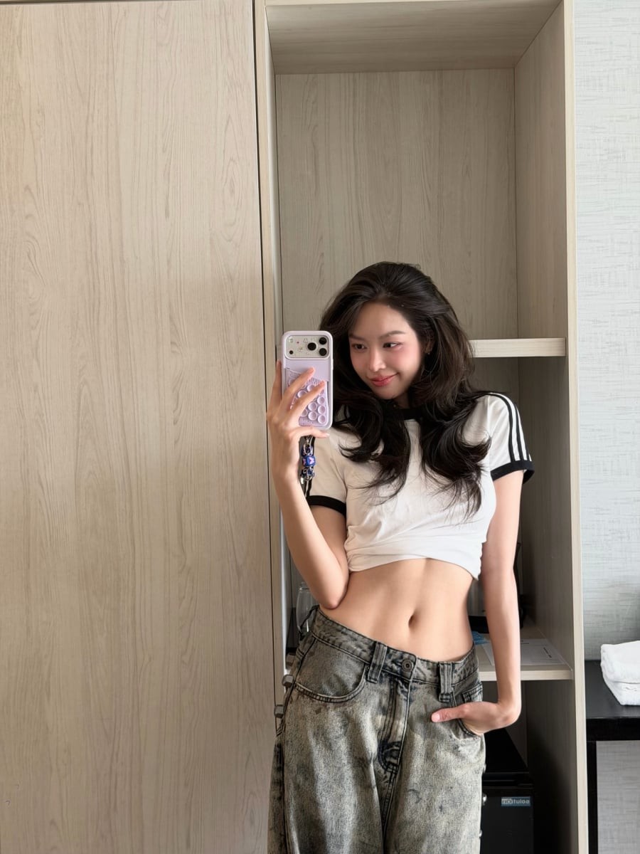 Thay vì giữ nguyên phom dáng ban đầu, chiếc áo được biến tấu thành kiểu croptop để tạo hiệu ứng vòng eo thon gọn và giúp bộ trang phục trở nên trẻ trung hơn.