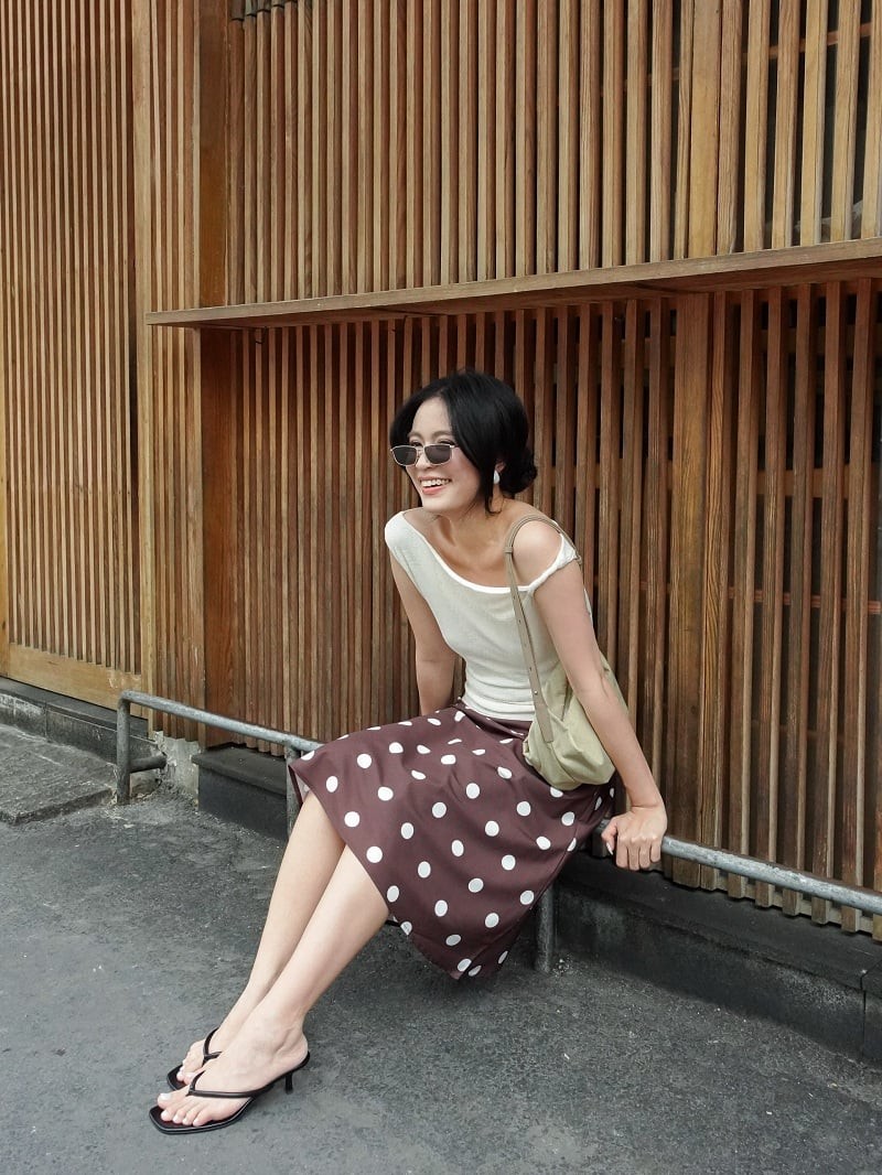 Trong một số bản phối khác, cô cũng mang hơi thở retro vào trang phục với chân váy chấm bi, áo lệch vai màu kem cùng túi đeo vai dáng mềm.
