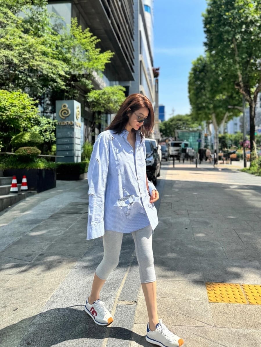  Cô từng phối sơ mi oversized kẻ sọc xanh nhạt cùng quần legging lửng màu xám và sneakers trắng.