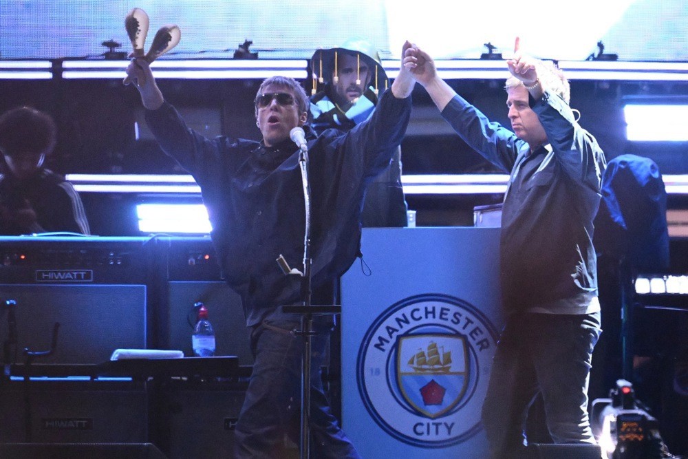 Ca sĩ Liam Gallagher (đeo kính đen)trấn an NHM Man City. Ảnh: EPA.